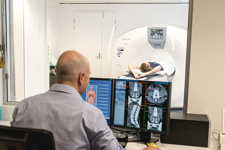 Radiographer monitoring a CT scan from the control room