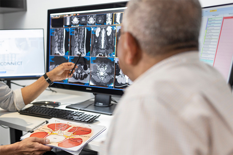 Radiologist talks to patient, showing the findings from their scan on the computer screen.